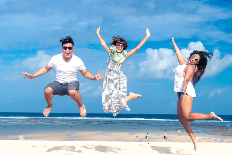 3 happy people at the beach jumping in the air